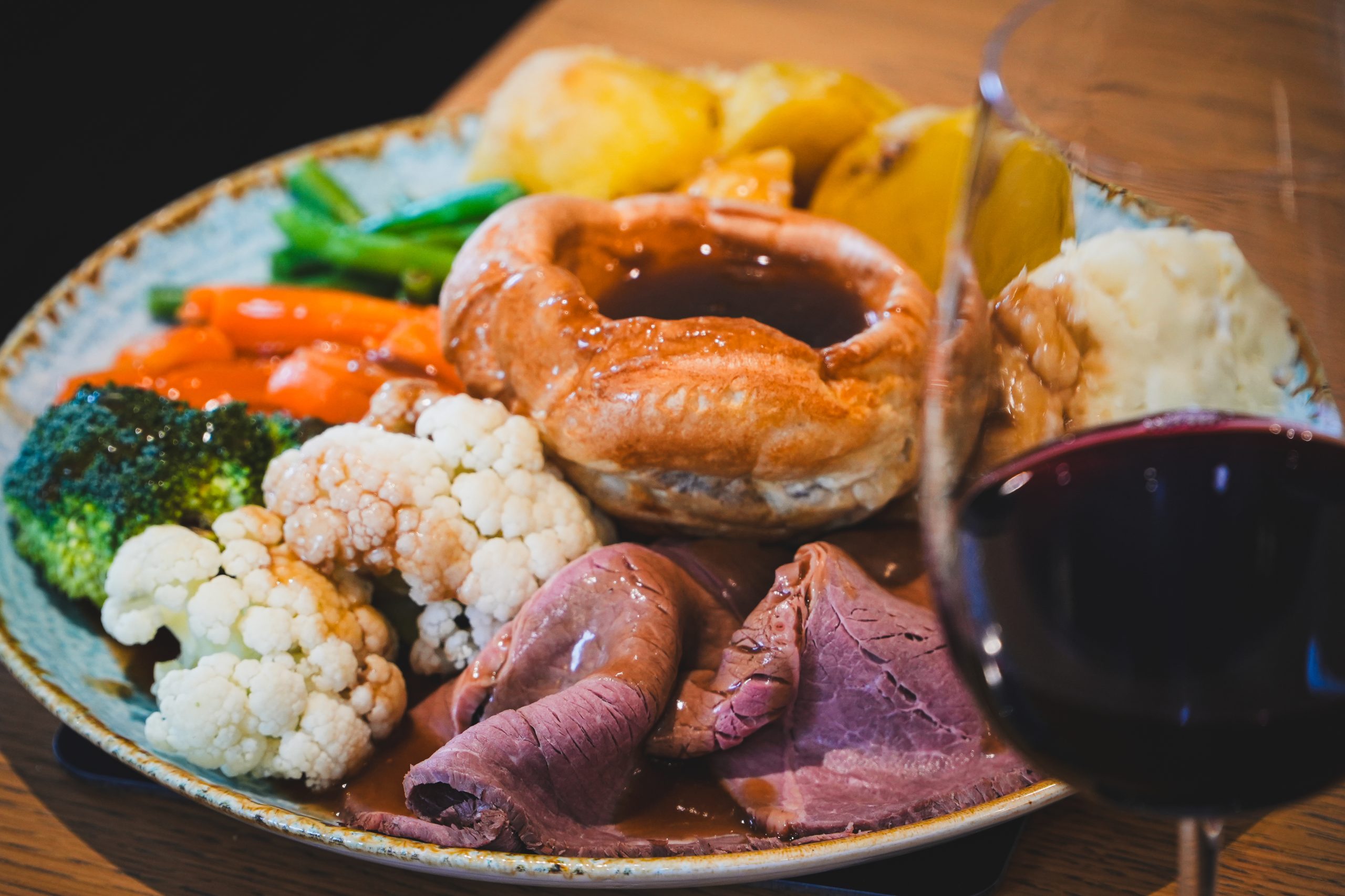 Roast beef and red wine Roast beef with Yorkshire pudding, cauliflower, broccoli, carrots, roast potatoes, mashed potatoes and a glass of red wine